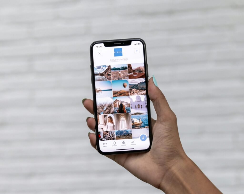 A hand holding a smartphone displaying travel photos against a white textured background.